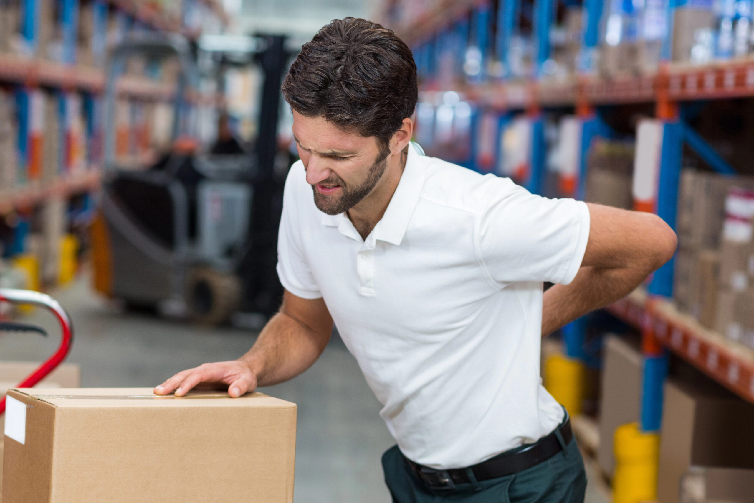 Manual handling - man suffering from backpain next to some cardboard boxes
